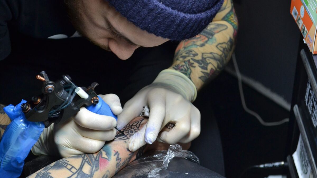 Un tatuatore al lavoro su un braccio